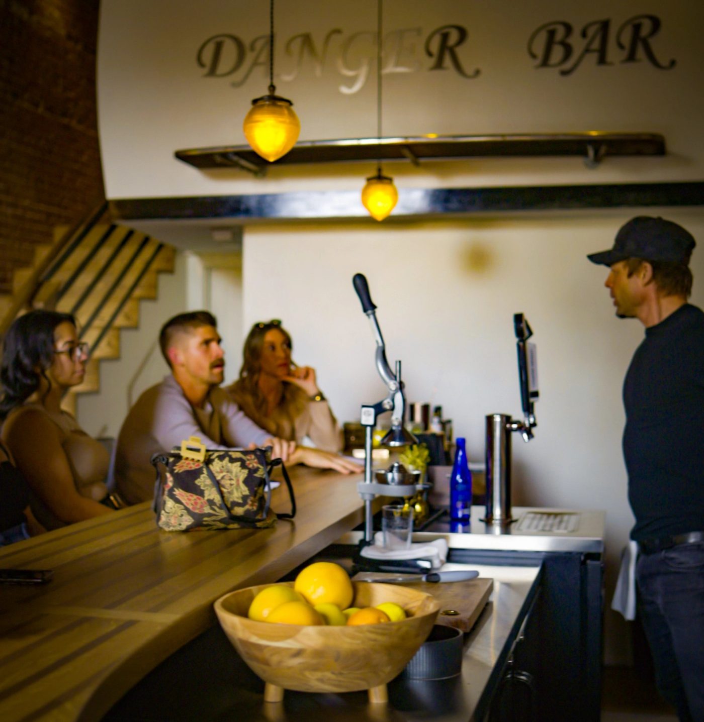 Guests at the bar with the staircase to the upstairs loft in the background.