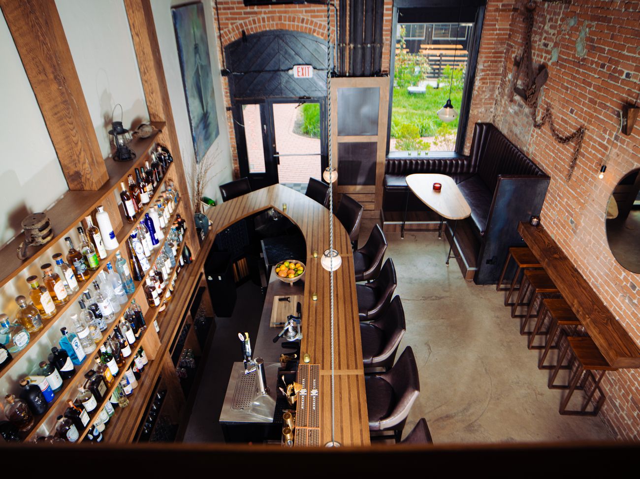 Overhead view of the back-bar shelves of top-shelf spirits under the brick arch.