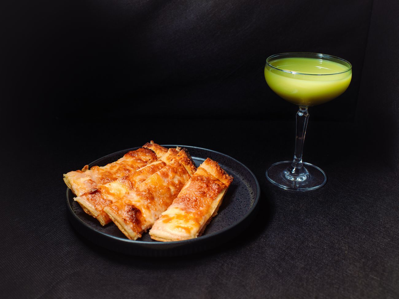 A flatbread and a cocktail on the table.