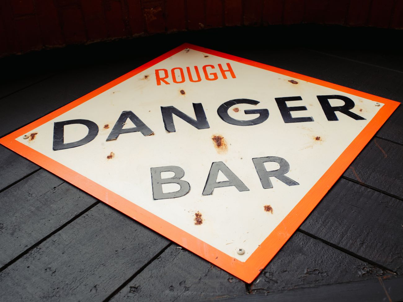 The orange and navy 'Rough Danger Bar' hazard sign on the wood floor.