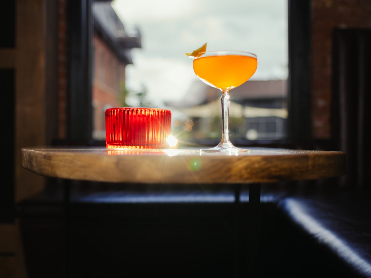 An amber cocktail with a citrus twist by the window.